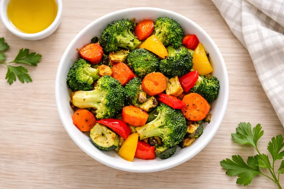 Roasted air fryer mixed vegetables in a white bowl on a light table